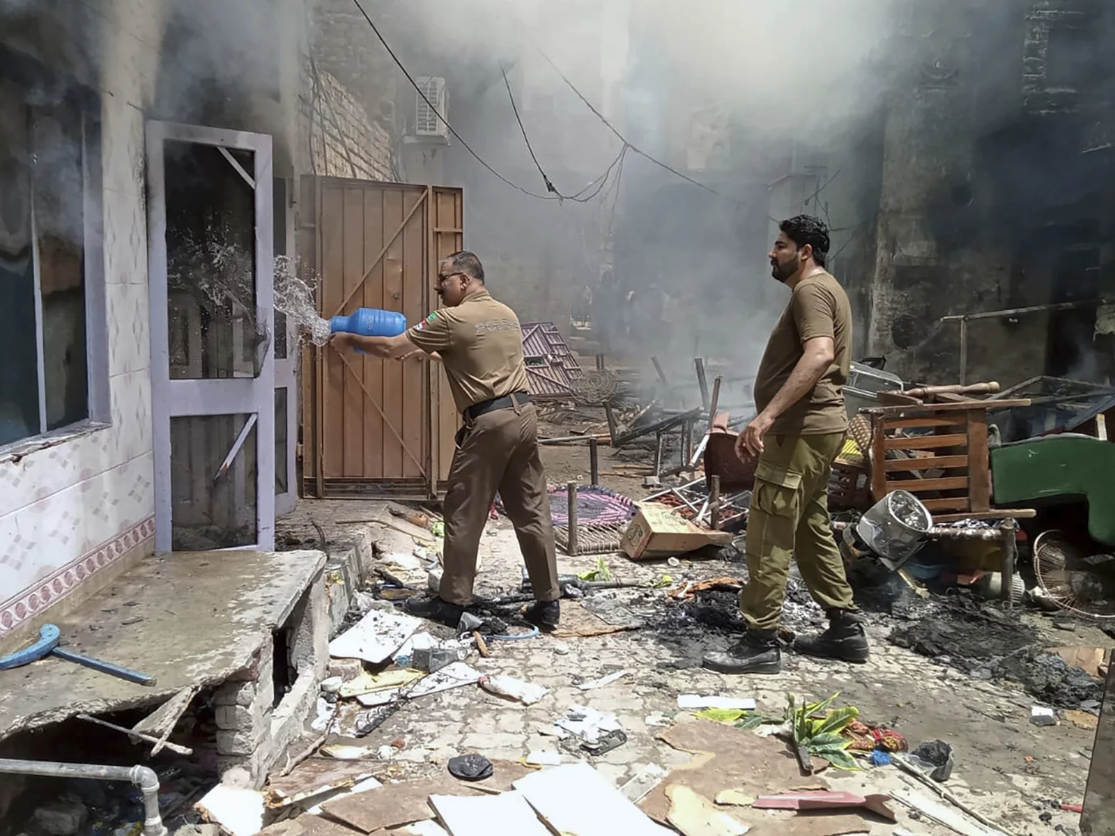 In this photo provided by district police office, a police officer pours water into a burning house in a Christian neighborhood in Jaranwala, near Faisalabad, Pakistan, Wednesday. A mob burned a church and damaged at least four others, police and local Christians said. The mob also demolished a man's house after accusing him of desecrating Islam's holy book, and attacked other Christian homes.